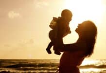 Mother and baby at sunset with ocean in the background.