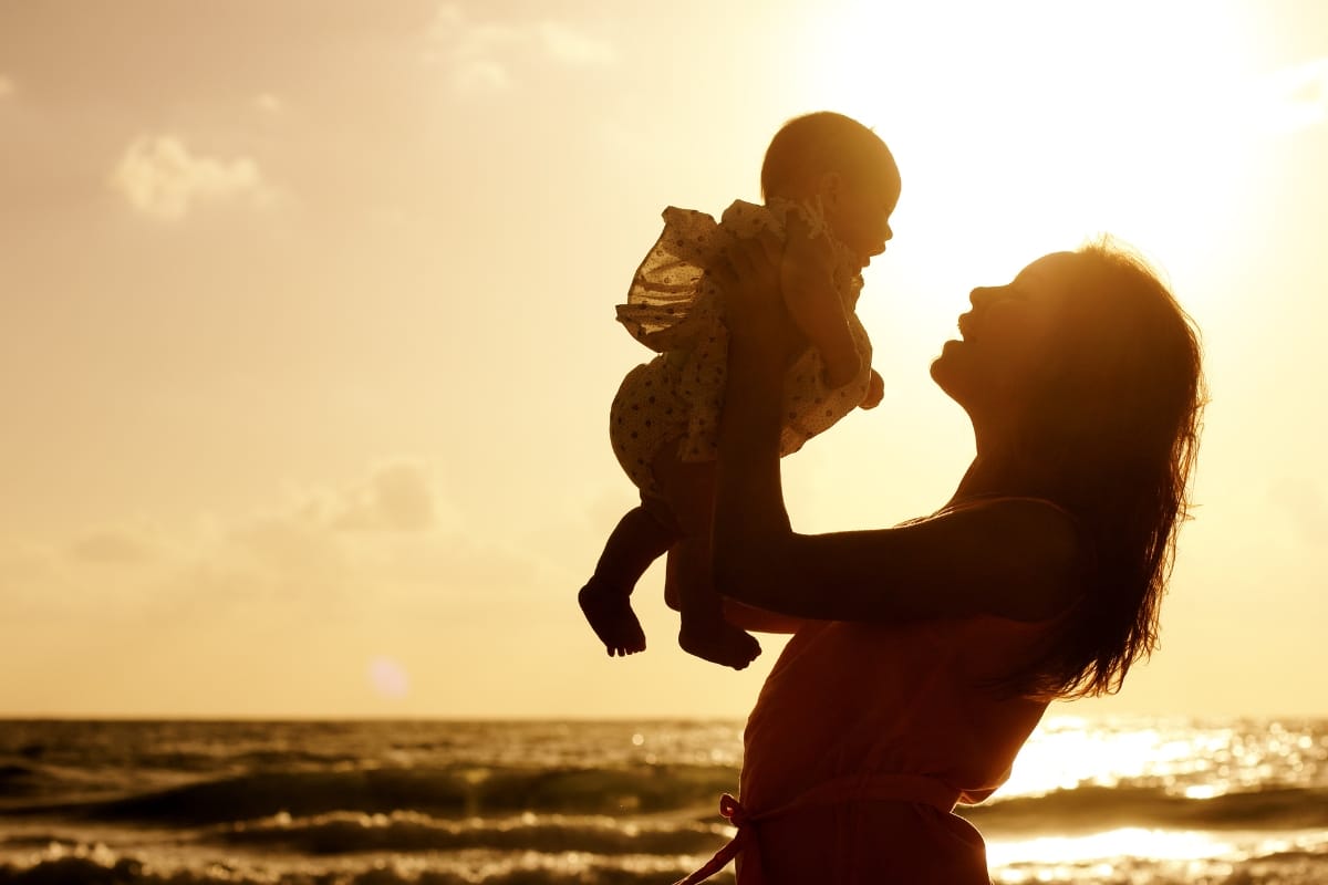 Mother and baby at sunset with ocean in the background.